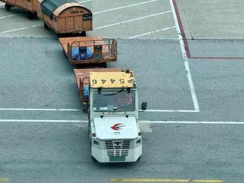 Tow tractor pulling air cargo containers on an airport apron